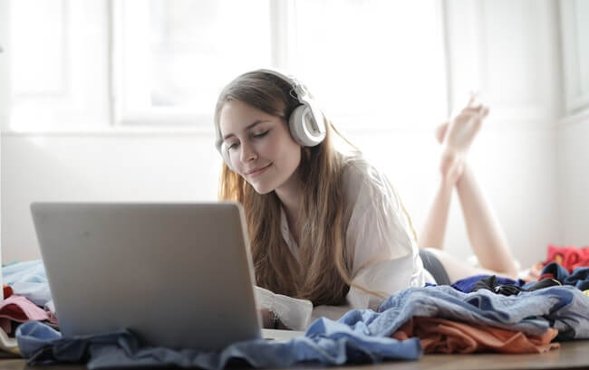 mulher branca de cabelos castanhos ouvindo música no notebook para aprender inglês