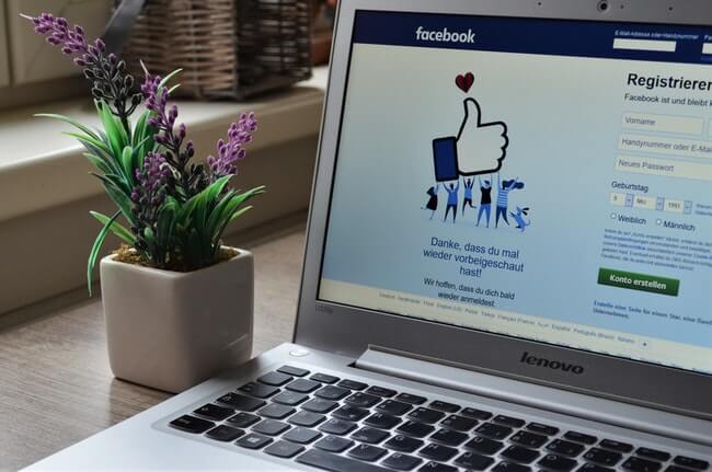 notebook aberto em uma mesa com a rede social facebook na tela